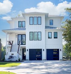 a large white house with blue garage doors