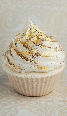 a cupcake with white frosting and gold sprinkles