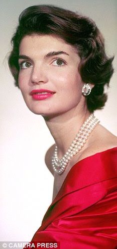 an old photo of a woman in a red dress and pearls on her head, wearing a pearl necklace