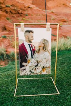 a wedding photo is placed on a gold frame in front of a red rock formation