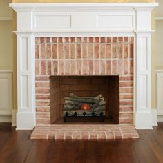 a fire place in the middle of a room with wood flooring and white walls