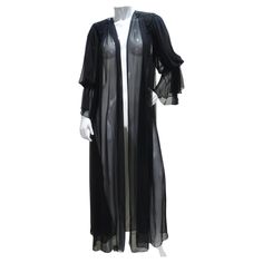 Introducing the 1980s Black Sheer Embellished Robe – a gorgeous and statement-making piece that exudes vintage charm and luxury. This robe is crafted from a black silky sheer fabric, featuring stunning billowing sleeves and intricate black bead embellishments on the shoulders. Versatile and glamorous, it can be worn around the house for a luxurious nighttime look or dressed up to add a touch of vintage elegance to your outfit. The black silky sheer fabric adds a touch of opulence to the robe, pr Long Sheer Robe, Luxury Black Elegant Robe, Black Sheer Robe, Sheer Robe With Fur, Versace Vintage, Luxury Vintage Black Kimono, Sheer Robe, Glamour Vintage, Vintage Versace