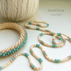 three strands of beaded necklaces next to a ball of yarn