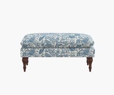 an upholstered bench with blue and white floral fabric on the top, against a white background