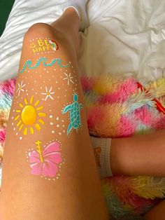 a person laying on a bed with some tattoos on their legs and feet, all covered in bright colors