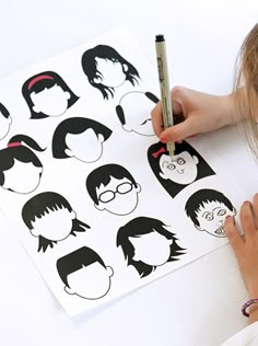 a person is drawing on some paper with their hair cut out to look like the faces of people