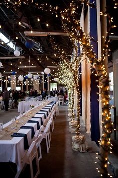 tables and chairs are set up for an event with lights strung from the ceiling above them