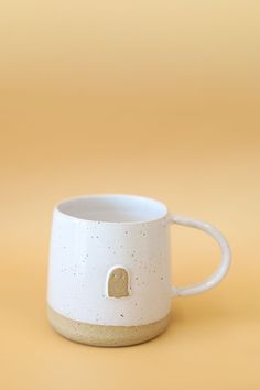 a white coffee cup with a gold heart on the inside sits against a yellow background