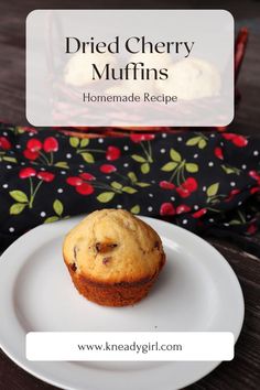 a muffin sitting on top of a white plate next to a red and black bag