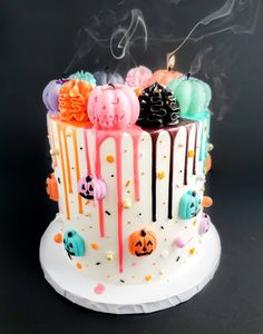 a white cake with colorful frosting and decorations on it's sides, topped with candles