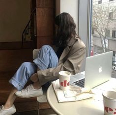 a woman sitting at a table in front of a laptop computer with her legs crossed