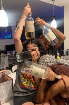 two women are sitting on the couch with bottles in their hands and one woman is covering her eyes