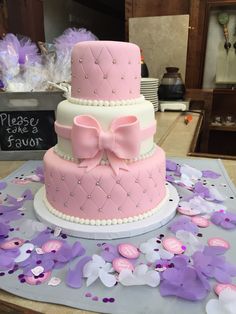 a three tiered cake with pink and white frosting on it's side