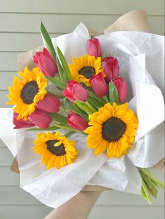 a bouquet of sunflowers and tulips in someone's hand