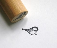 a rubber stamp with a small bird on it's side next to a piece of paper