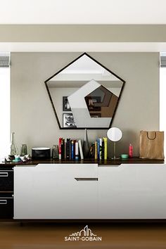 a living room with a large mirror on the wall next to a white cabinet filled with books