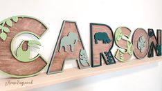 the letters are made out of wood and have animals on them, as well as leaves