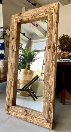 a mirror sitting on top of a floor next to a potted plant in a room