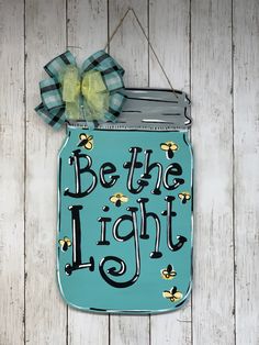 a mason jar hanging on the side of a wooden wall that says be the light