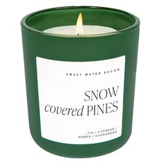 a green candle with the words snow covered pines printed on it's front and side