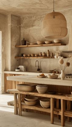 a wooden table topped with bowls and plates under a hanging light over a kitchen counter