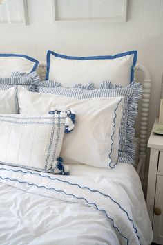 a white bed with blue trim and ruffles on the comforter is shown