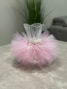 a pink tutu skirted vase sitting on top of a table next to a potted plant