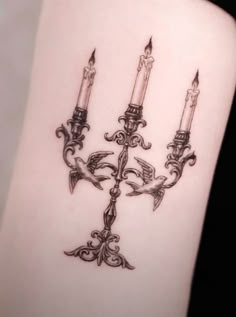 a woman's arm with three candles tattooed on the left side of her body