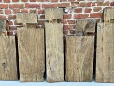 several pieces of wood that are standing next to each other in front of a brick wall