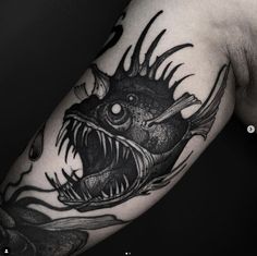 a man's arm with a black and white tattoo design on it, depicting a fish