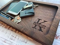 a personalized wooden tray with money, cell phone and keys on it that says keshart