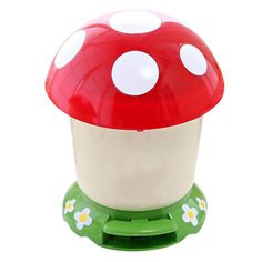 a red and white mushroom sitting on top of a green stand