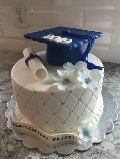 a graduation cake with blue and white decorations on the top is sitting on a counter