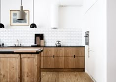 a kitchen with wooden cabinets and black counter tops in the center, along with white subway walls