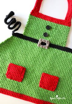 a crocheted green and red bag sitting on top of a white table next to scissors