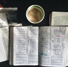 an open book sitting on top of a table next to a cup of coffee