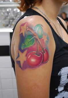 a woman with a tattoo on her arm has cherries and leaves painted on it