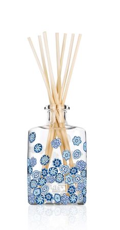 reed sticks in a glass container with blue flowers