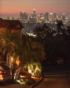 a car parked in front of a house with the city lights behind it