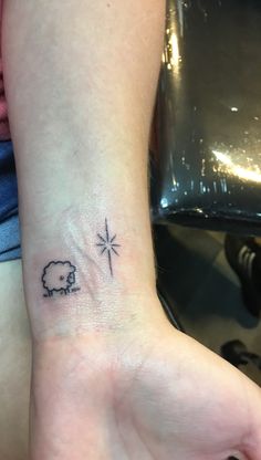 a small tattoo on the wrist of a woman's left hand with an elephant and star