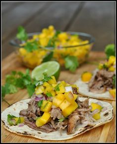 two tacos with meat, pineapple salsa and cilantro on a cutting board