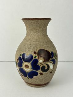 a vase with blue flowers painted on the outside and inside, sitting on a white surface