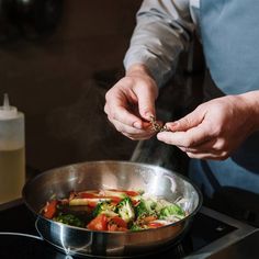 a person cooking food in a pan on the stove