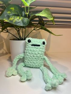 a crocheted toy sitting next to a potted plant