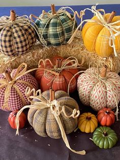 pumpkins and gourds are arranged on hay bales with twine ribbons