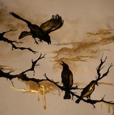 two black birds sitting on top of a bare tree branch with gold paint splatters