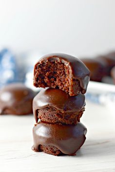 three chocolate doughnuts stacked on top of each other with one bite taken out