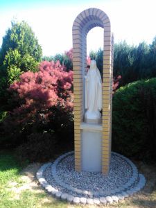 there is a statue in the middle of a small garden with rocks and stones around it