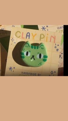 there is a green cat brooch with the word claypin on it's face