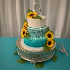 a three tiered cake with sunflowers on the top and green leaves around it